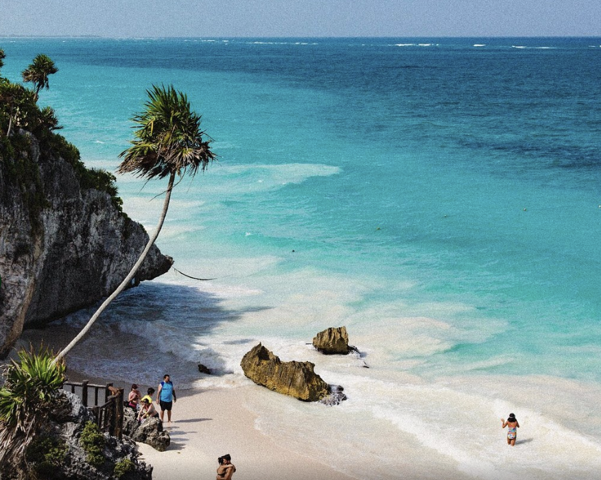ista panorámica de la playa bajo la zona arqueológica de Tulum con mar turquesa y palmeras en Quintana Roo, México.