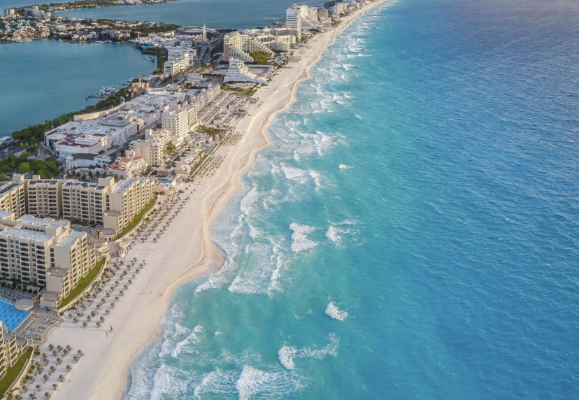 Aerial panoramic view of Cancun Hotel Zone featuring white sand beaches, luxury resorts, and the turquoise Caribbean Sea.