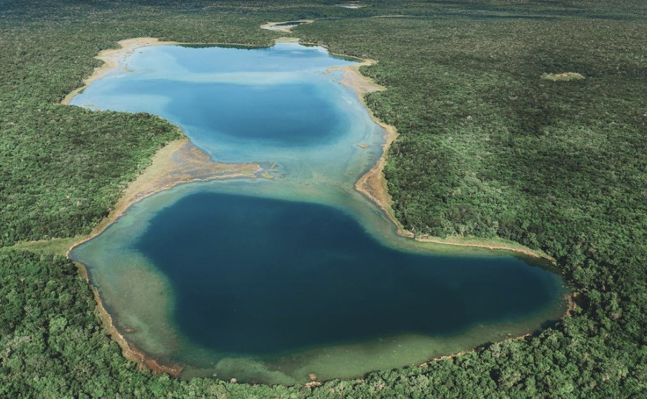 Vista aérea de dos lagunas de agua azul turquesa rodeadas de densa selva tropical en la Península de Yucatán, México.