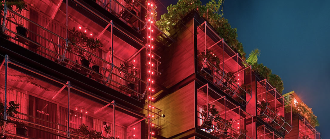Modern apartment building with red neon lighting and industrial design at night.