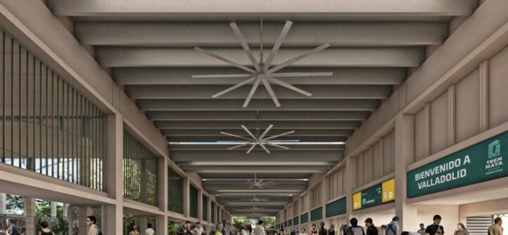 Passengers at the platform of the modern Mayan Train station in Valladolid, Yucatan, featuring contemporary architecture with high ceilings and industrial fans.
