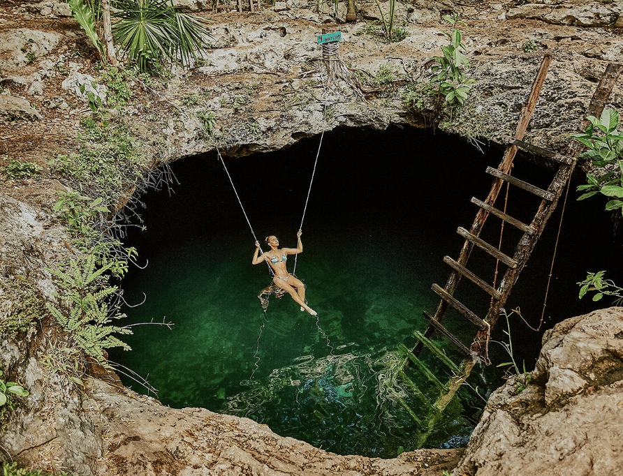 Stalactite formations on the ceiling of a flooded cavern with turquoise waters in a Mexican cenote.