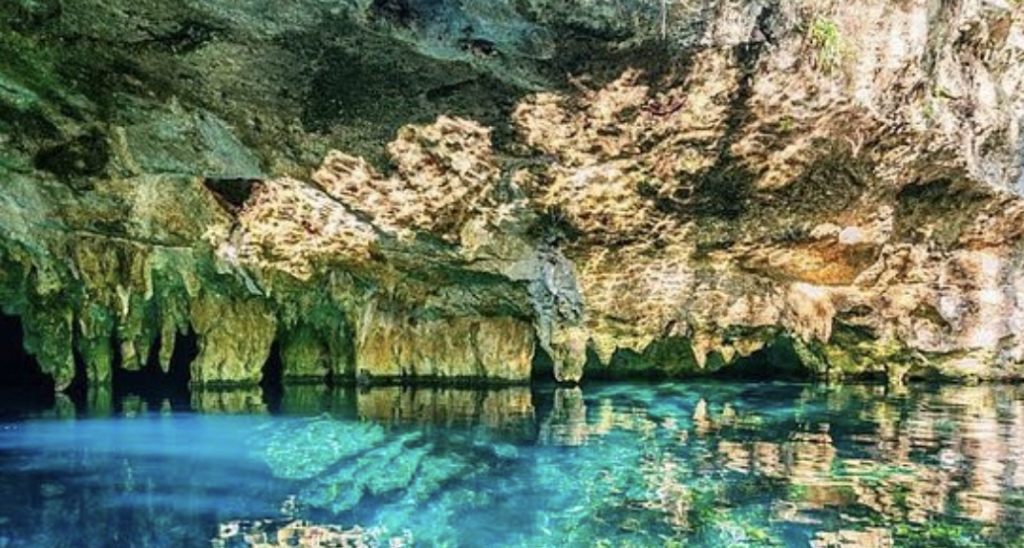 Interior view of an underground cavern cenote with stalactites and crystal clear turquoise water in Riviera Maya, Mexico.